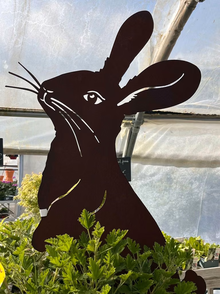 Silhouette décorative de lapin en métal parmi les plantes